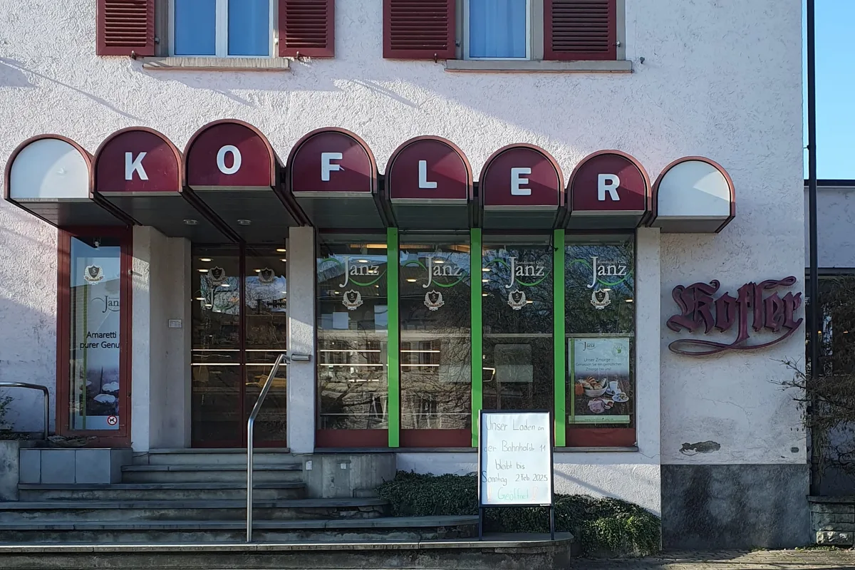 Man sieht den Eingang einer Konditorei mit einem Schild davor.